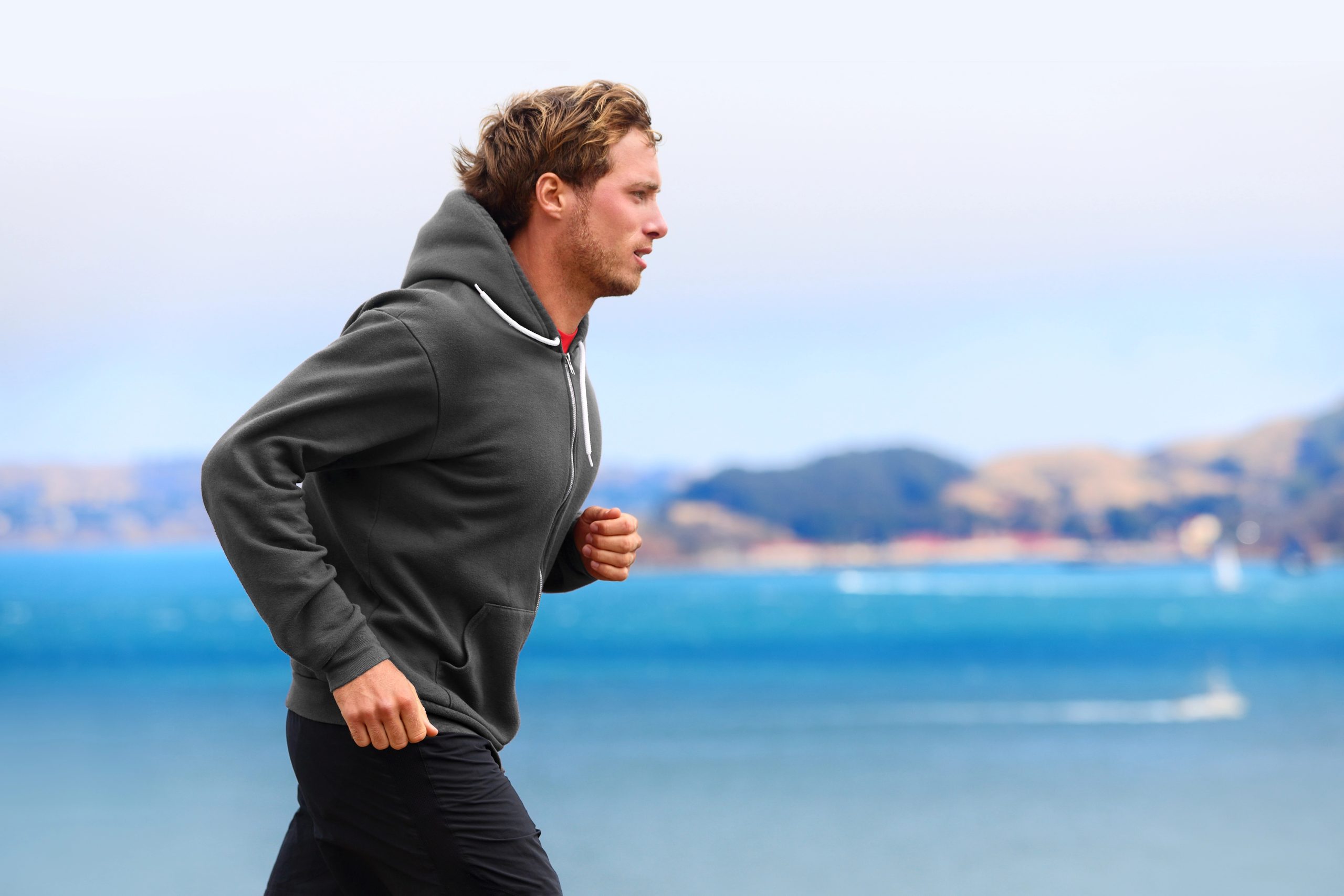 Man running in hoodie near water