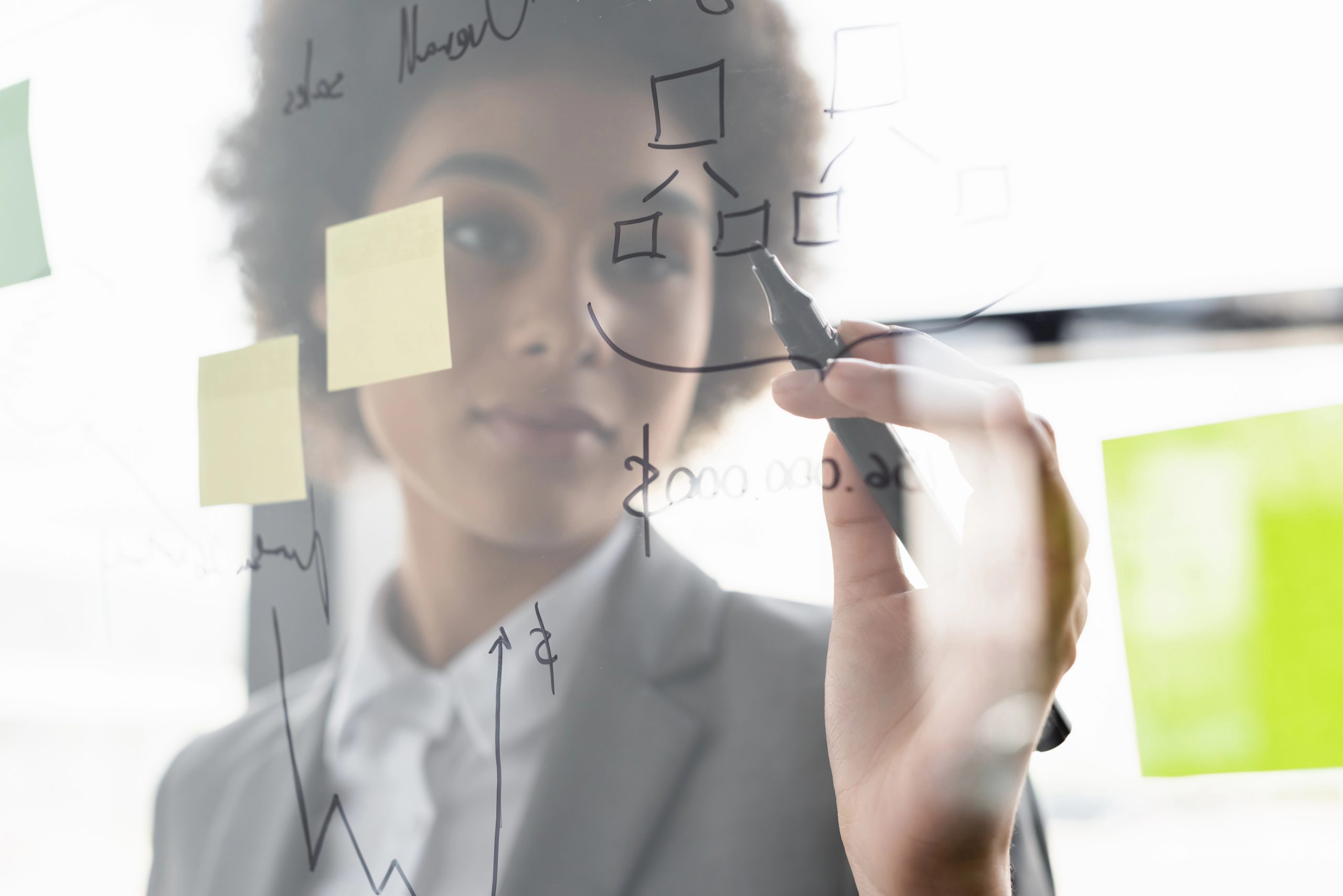 Blurred african american businesswoman writing on glass board