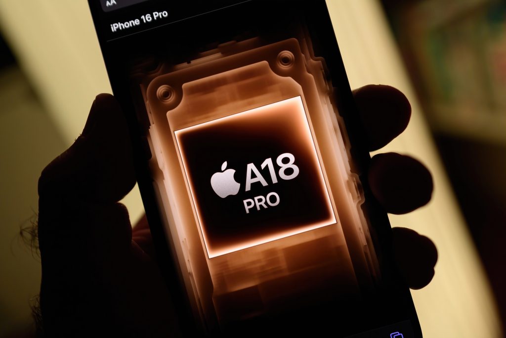 Paris, France - Sep 8, 2024: Vertical shot of a male hand holding the iPhone 16 Pro Max with a yellow background, highlighting the new power of the A18 Pro silicon chip inside, showcasing advanced