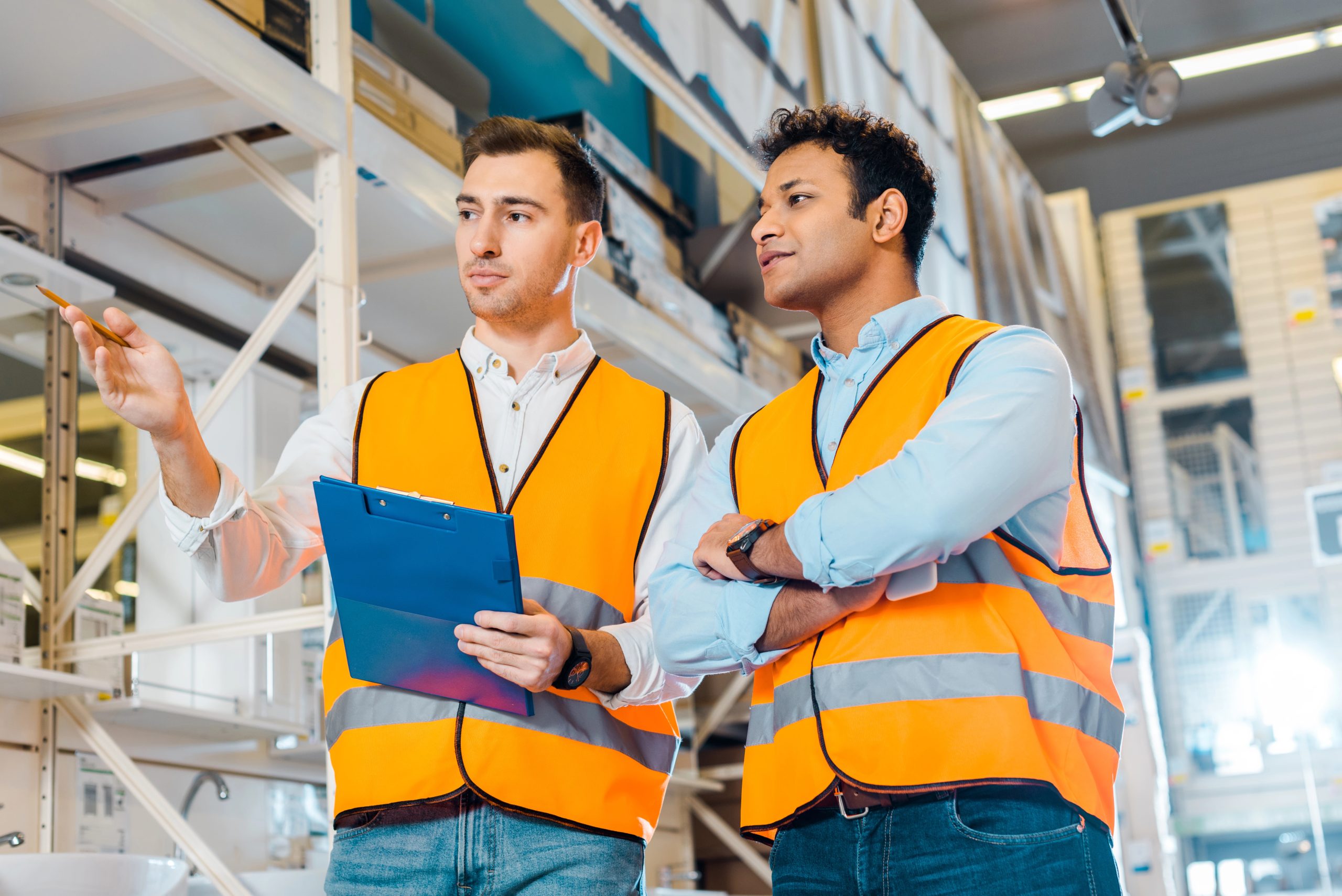 attentive multicultural warehouse workers in safety vests working in plumbing department